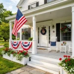 Stunning patriotic front porch with American flag, red geraniums, white planters, and blue bunting on a summer day